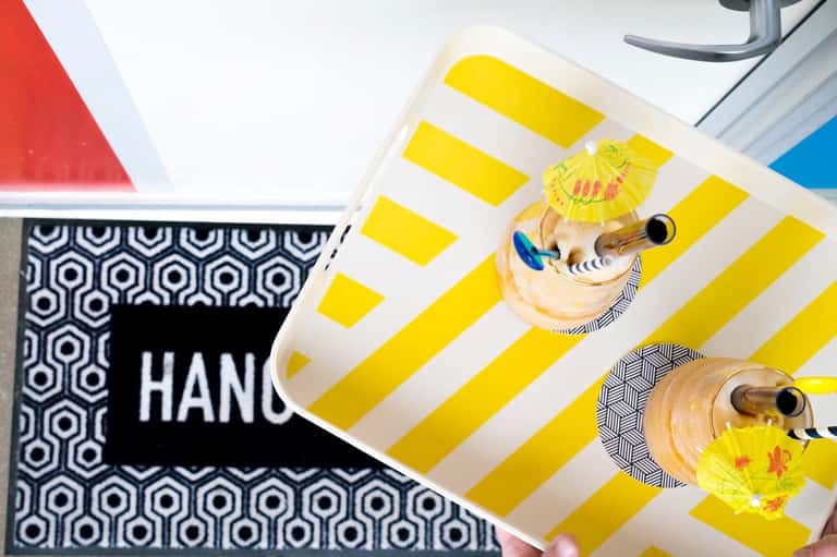 Tropical cocktails with umbrella garnish on yellow and white striped tray