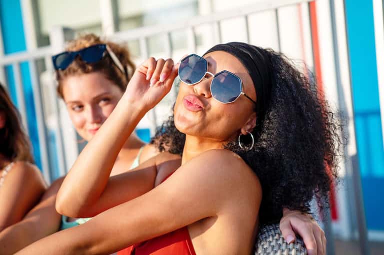 Women in sunglasses relaxing poolside on a bright sunny day at the resort