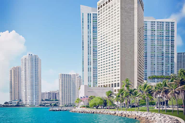 Beachfront high-rise hotel buildings along turquoise waterfront with palm trees and manicured lawns