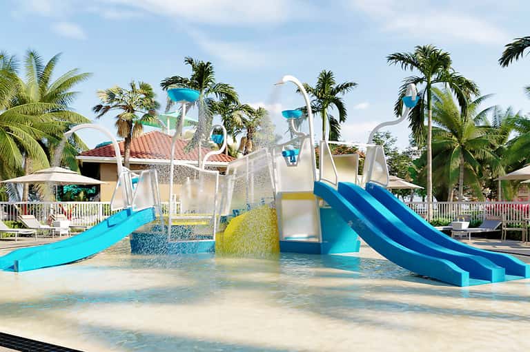 Water park with colorful slides, palm trees, and shallow splash area at tropical resort
