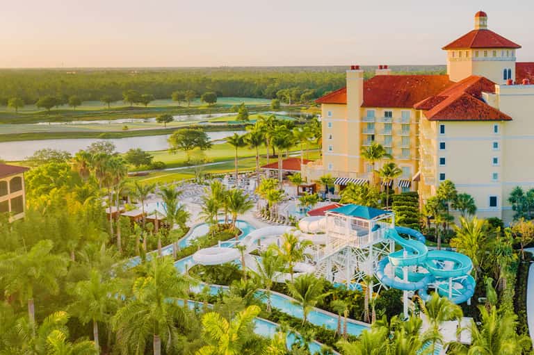 Aerial view of castle-style resort with water slides, pools, and manicured grounds