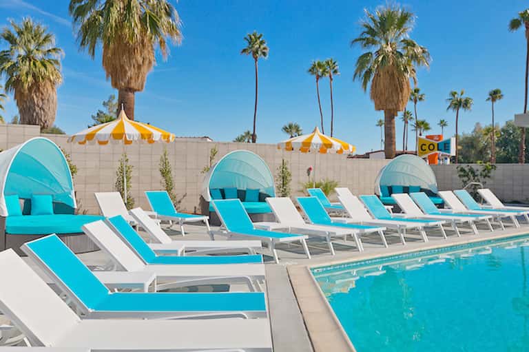 Turquoise lounge chairs with cabanas and yellow umbrellas by pool