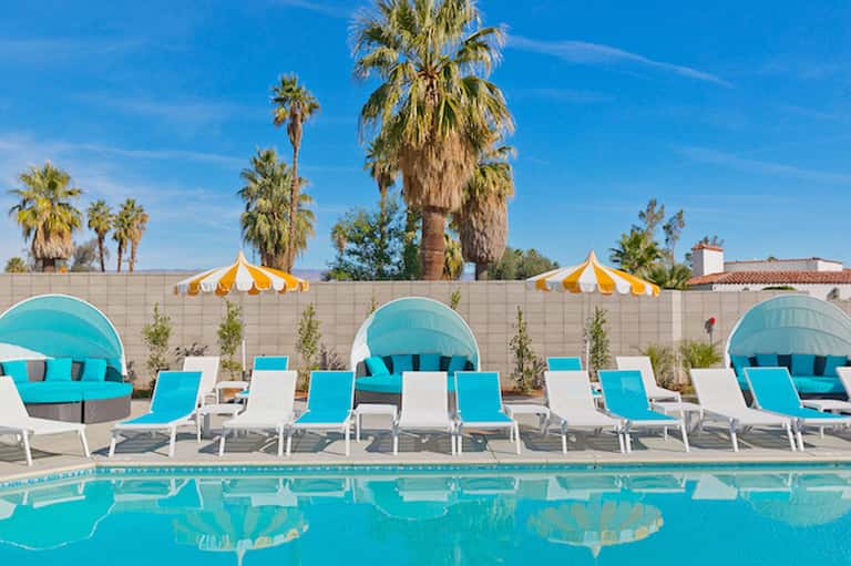 Pool deck with turquoise loungers, yellow umbrellas, and palm trees
