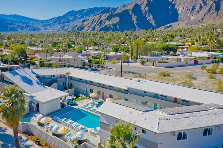 Desert resort with white buildings, blue pool, and mountains in background