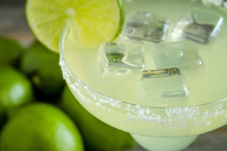 Margarita cocktail with lime wheel and salt rim, ice cubes visible in the glass