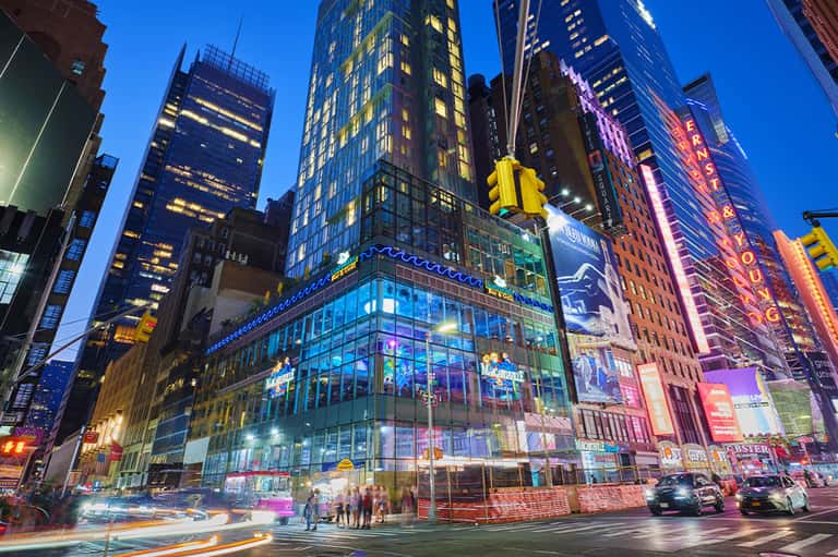 Times Square NYC at night with illuminated skyscrapers, neon signs, and yellow taxis on busy street