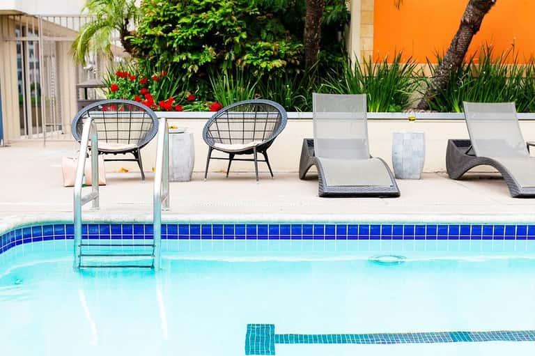 Poolside seating with modern lounge chairs and round accent tables by bright blue pool
