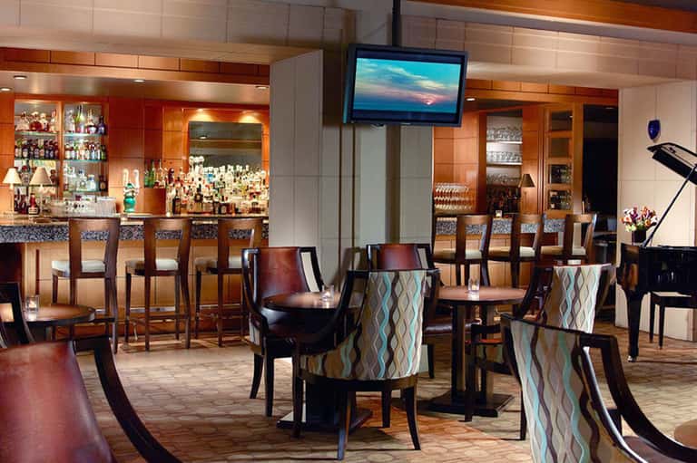 Upscale hotel lounge with full bar, wooden accents, comfortable seating, and flat-screen television