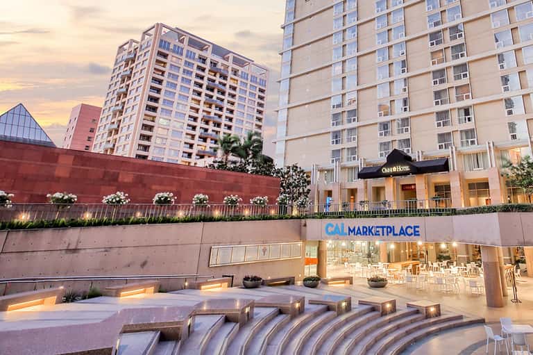 Contemporary hotel courtyard with CAL Marketplace entrance and sculptural water features at dusk