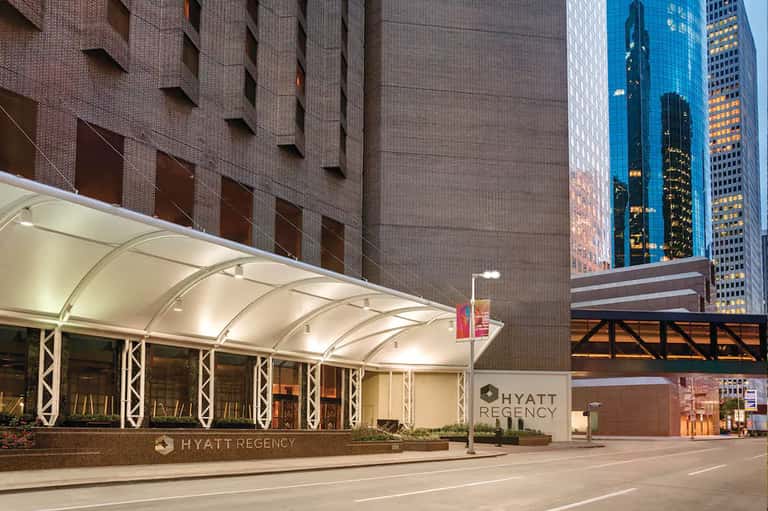 Hyatt Regency hotel entrance with illuminated canopy at dusk in urban downtown setting