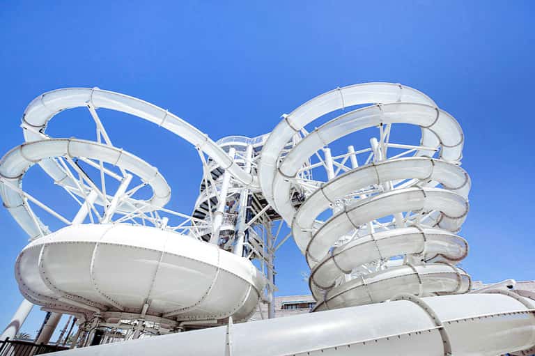 White water slides with multiple twisting tubes against clear blue sky at water park