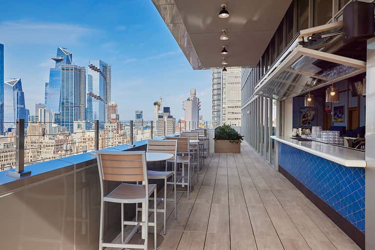 Modern rooftop bar with blue accents overlooking city skyline and tall buildings