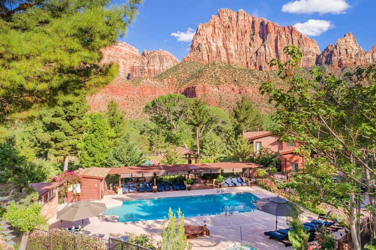 Resort pool with red rock mountain backdrop, surrounded by lounge chairs and desert landscaping