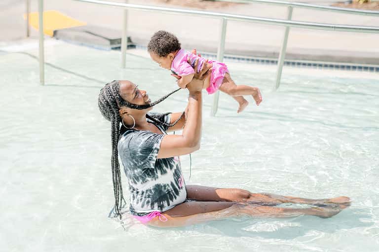 Woman and child playing in shallow pool water at resort
