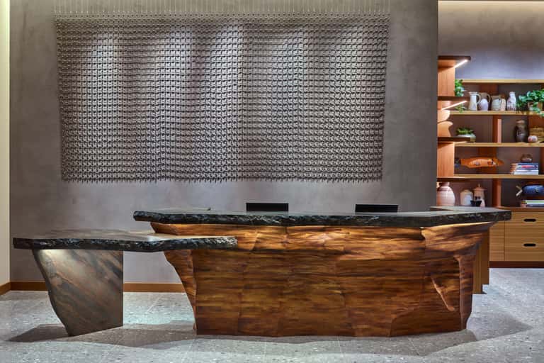 Contemporary hotel reception desk with sculptural wood design and textured wall backdrop