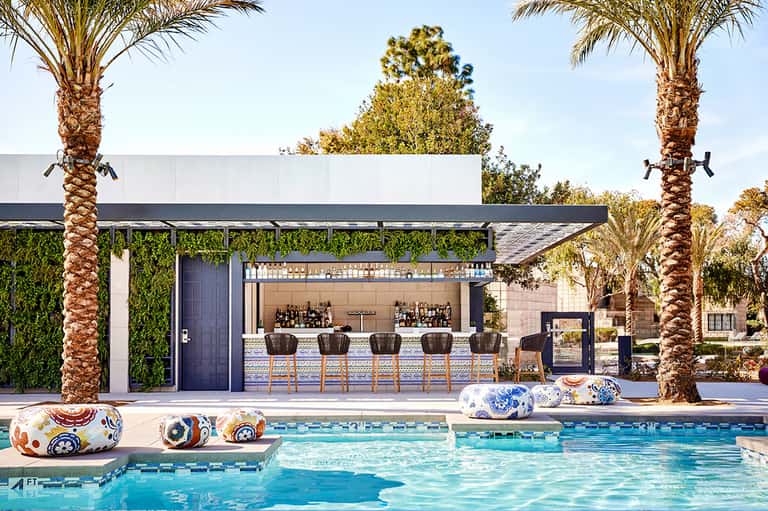 Modern pool bar with white roof, green living wall, and palm trees flanking the structure