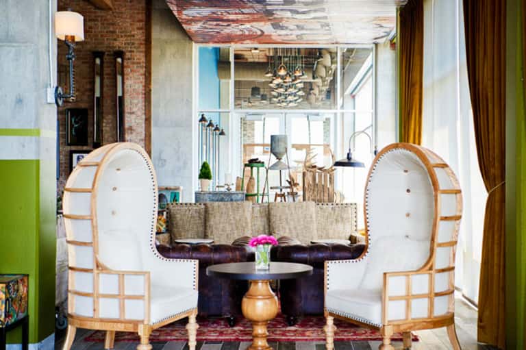 Elegant lounge area with two cream and wood accent chairs facing a round black table with pink flowers