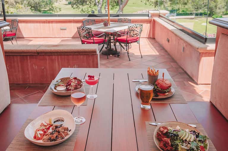 Rooftop dining with plated cuisine, cocktails, and panoramic views of green landscape