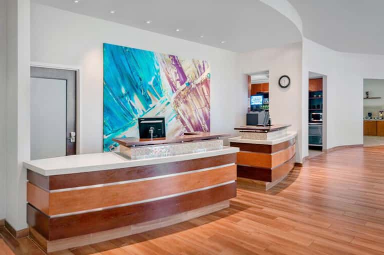 Modern hotel reception desk with wood and marble finishes, colorful abstract artwork, and contemporary design