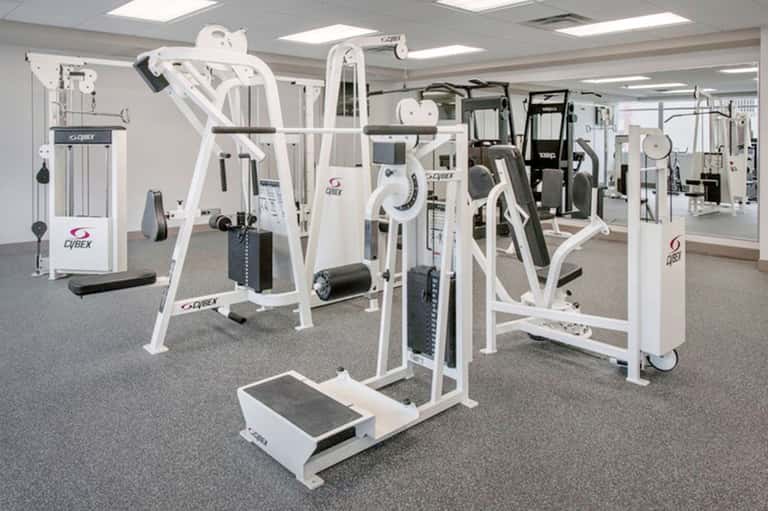 State-of-the-art fitness center with white Cybex exercise equipment and mirrored walls