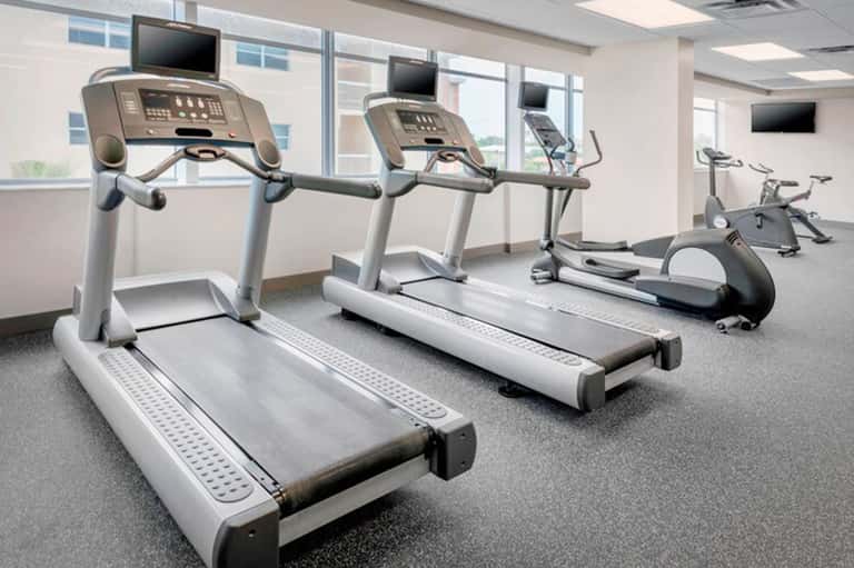 Bright fitness center with multiple treadmills facing large windows overlooking the landscape