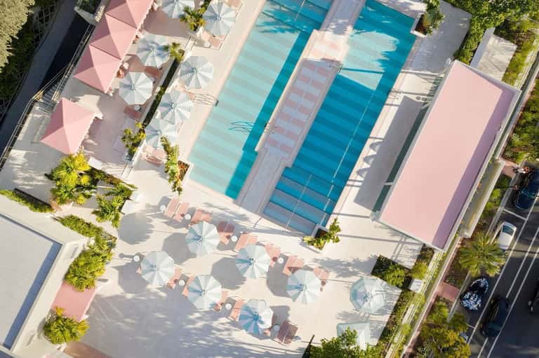 Aerial view of resort pools and pink-roofed lounging areas with umbrellas
