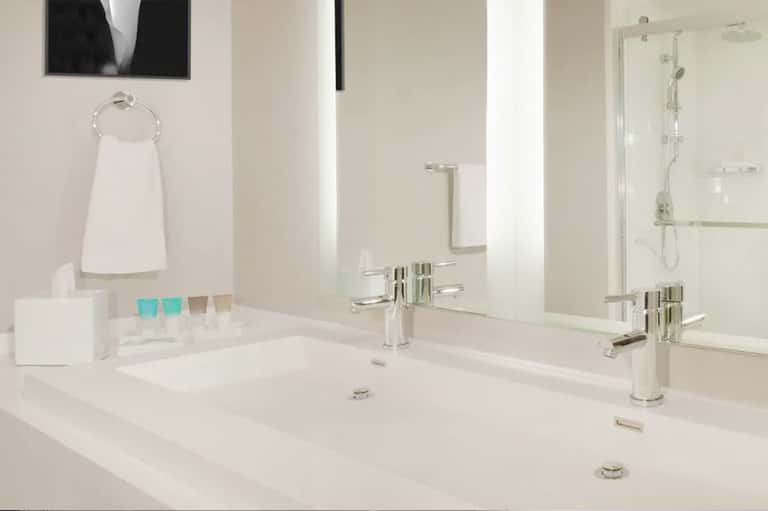 Modern bathroom with dual vanities, white countertops, and walk-in shower
