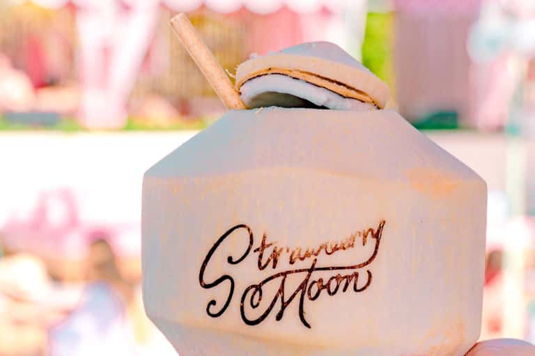 Strawberry cocktail with branding, focused shot with blurred pink tropical background