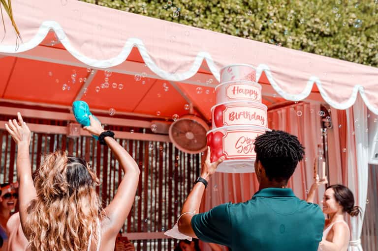 Outdoor birthday celebration with bubble machine under red and white striped tent canopy