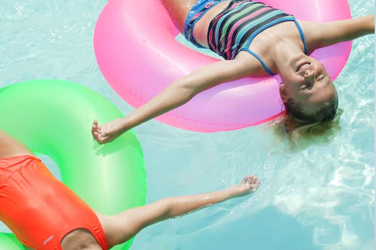 Child floating on colorful inflatable rings in bright turquoise pool water