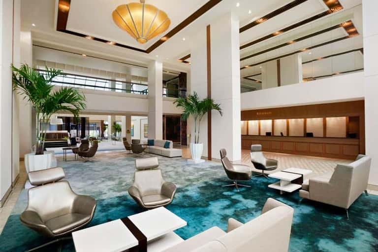 Modern hotel lobby with high ceilings, gold fixtures, and contemporary seating areas