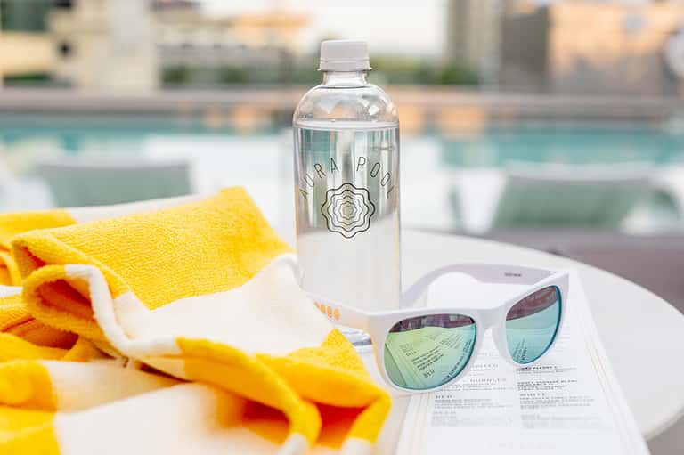 Poolside items including water bottle, sunglasses, yellow towel, and resort loungers