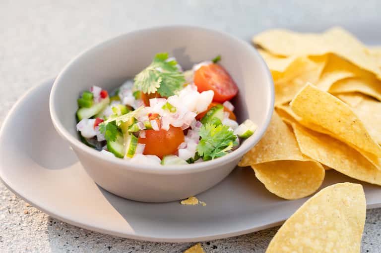 Fresh pico de gallo in white bowl served with tortilla chips
