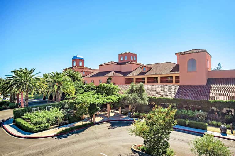 Spanish Colonial-style resort exterior with pink buildings, blue domes, and manicured gardens