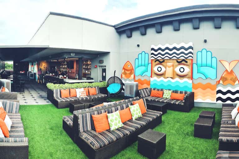 Outdoor pool deck with striped loungers, colorful wall art, and tropical building architecture