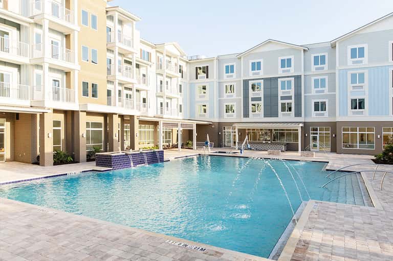 Modern apartment complex with pool, loungers, and multi-story residential buildings