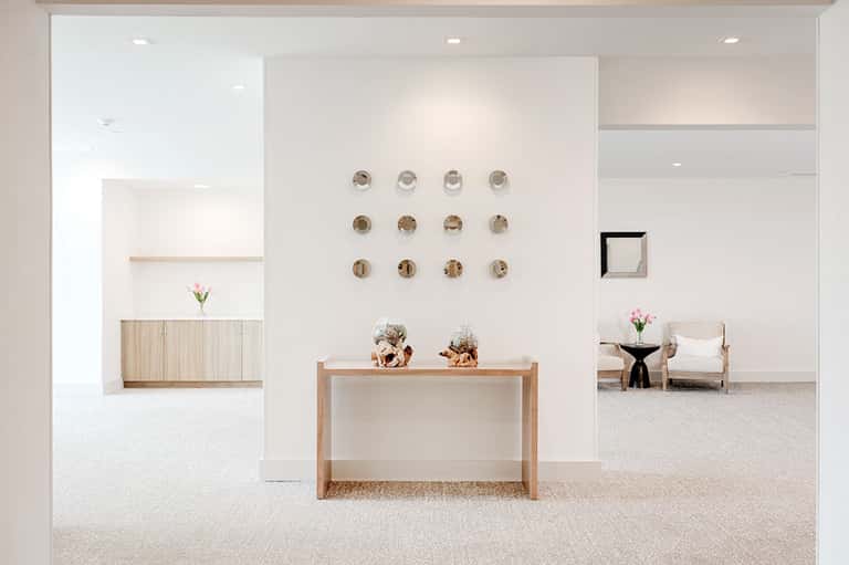 Minimalist white spa lobby with wooden console table, circular wall art, and modern furnishings