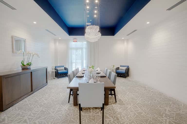 Modern private dining room with white shiplap walls, blue ceiling, crystal chandelier