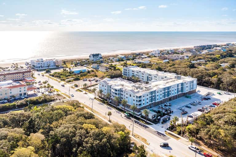 Aerial view of modern beachfront hotel complex near ocean with parking lot and vegetation