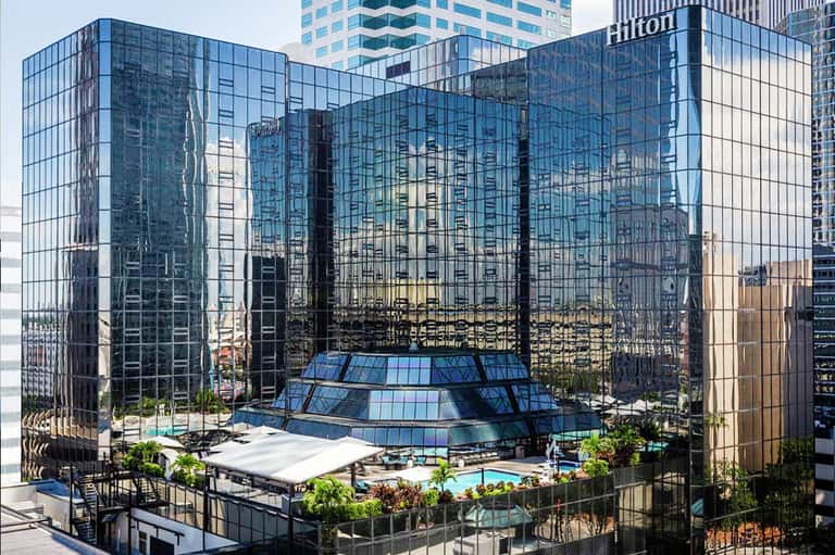 Modern hotel courtyard with glass architecture, central pool, and surrounding tall buildings