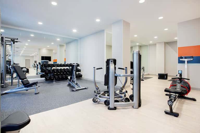 Modern fitness center with dumbbells, cardio machines, mirrors, and bright lighting