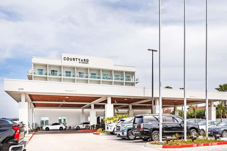 Modern Courtyard by Marriott hotel exterior with covered parking area and vehicles