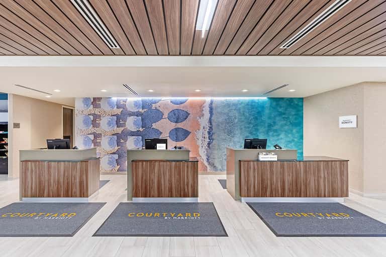 Hotel check-in desk with wood accents and coastal-themed artwork featuring turquoise tones
