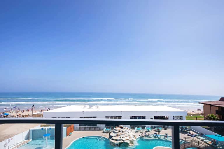 Beachfront resort pool deck with ocean view and white building structure in background
