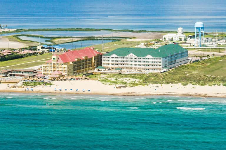 Beachfront resort with red-roofed building overlooking ocean and marsh landscape