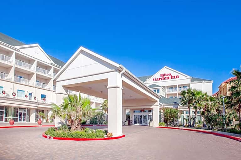 Hilton Garden Inn entrance with white columns, palm trees, and brick paved courtyard