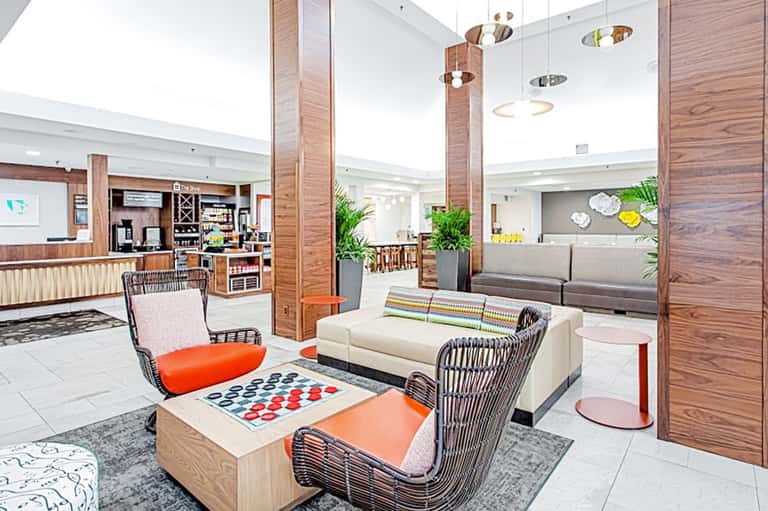 Modern hotel lobby with wood accents, contemporary furniture, and tropical plant decor