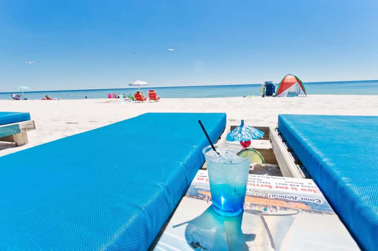 Tropical beach scene with blue kayaks, colorful cocktail drink, and ocean view