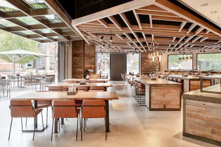 Contemporary restaurant and bar with wooden beams, communal tables, and outdoor patio seating