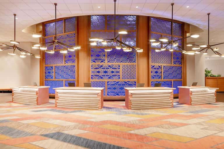 Modern hotel lobby with curved wooden reception desks and blue patterned glass wall